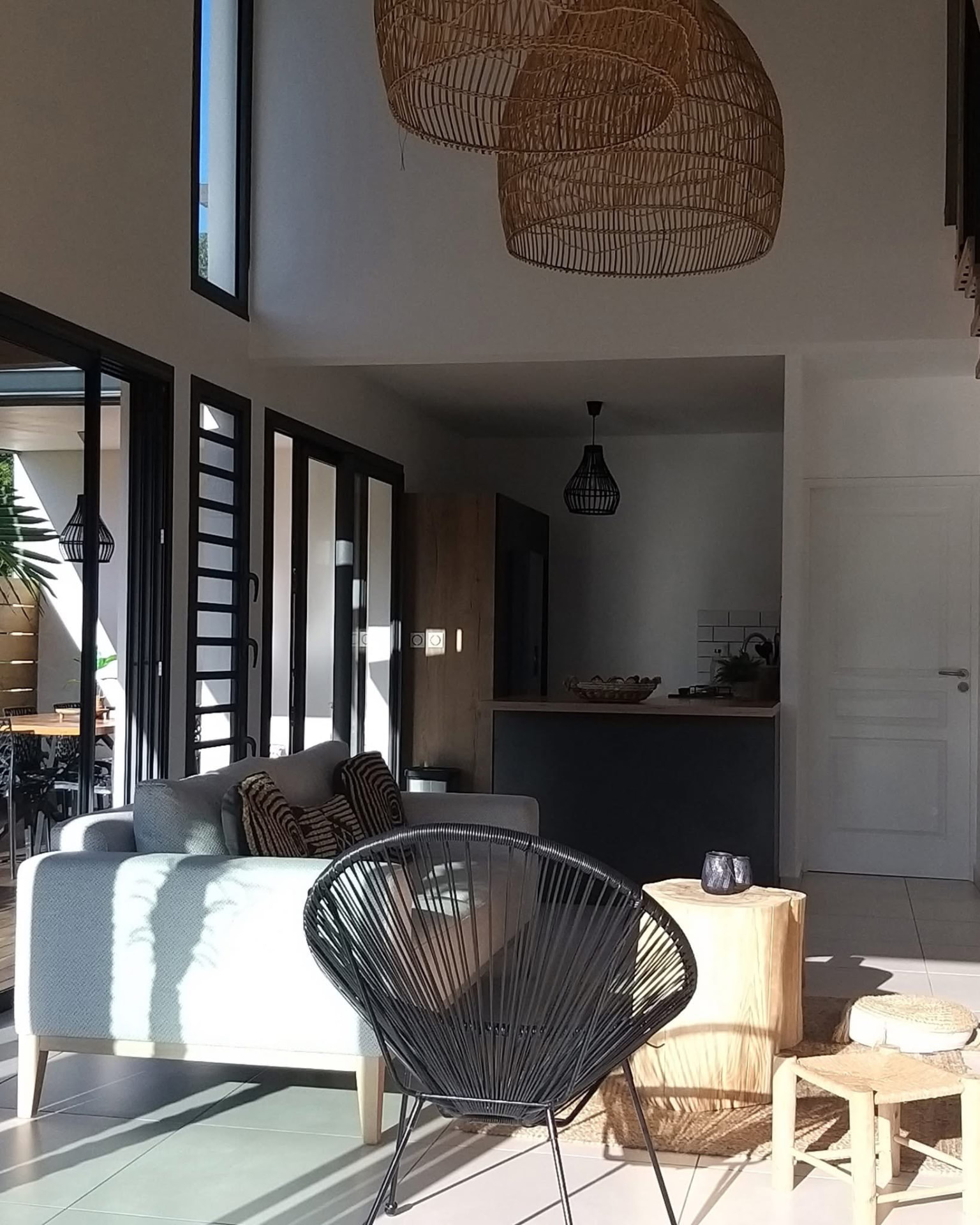 Salon baigné de lumière avec fauteuil Acapulco et cuisine en fond