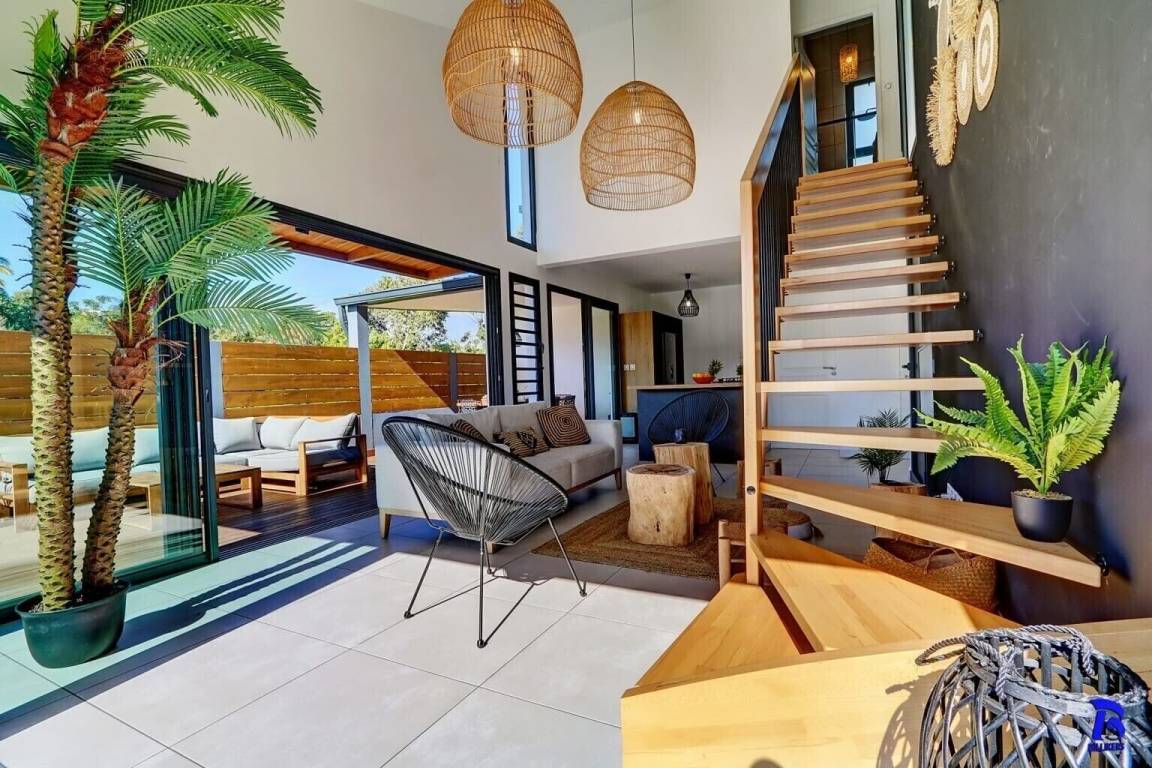 Séjour avec escalier en bois, suspensions en rotin et palmier