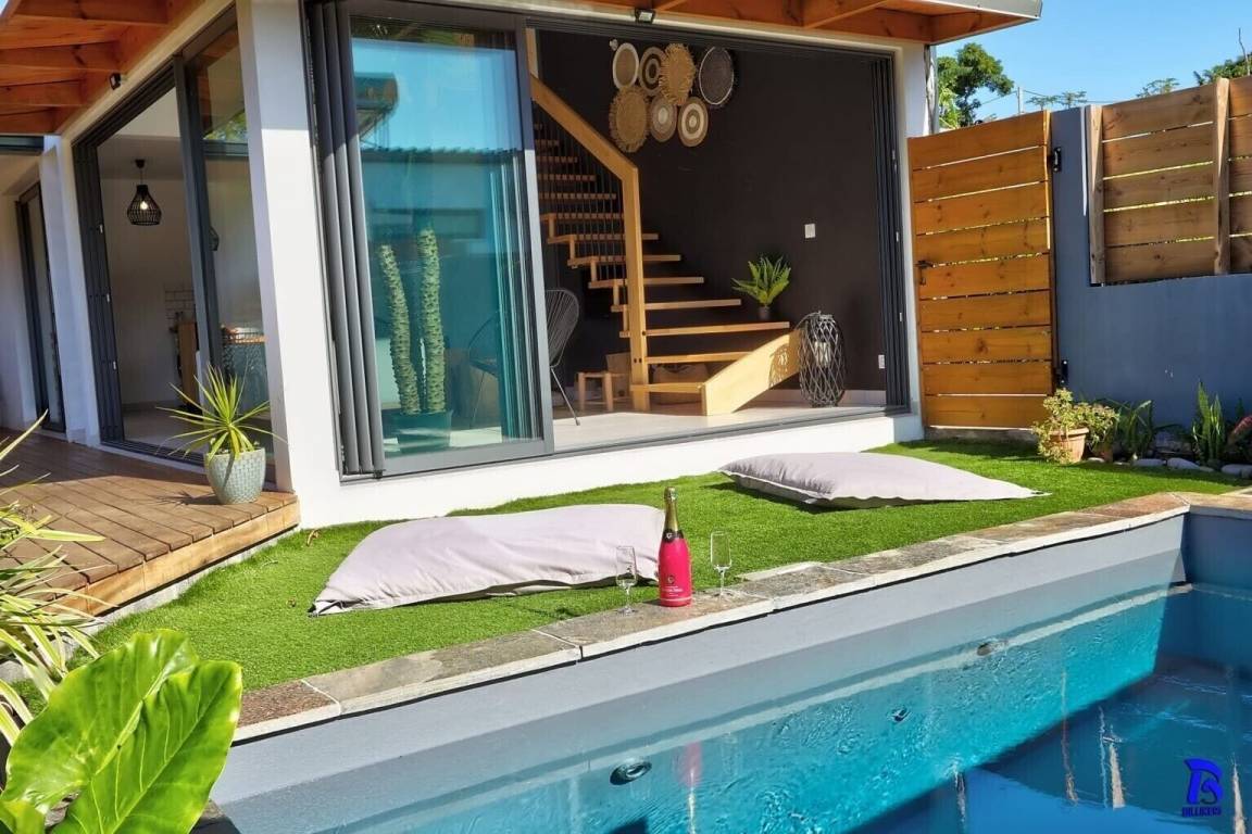 Jardin synthétique en bord de piscine avec poufs de détente