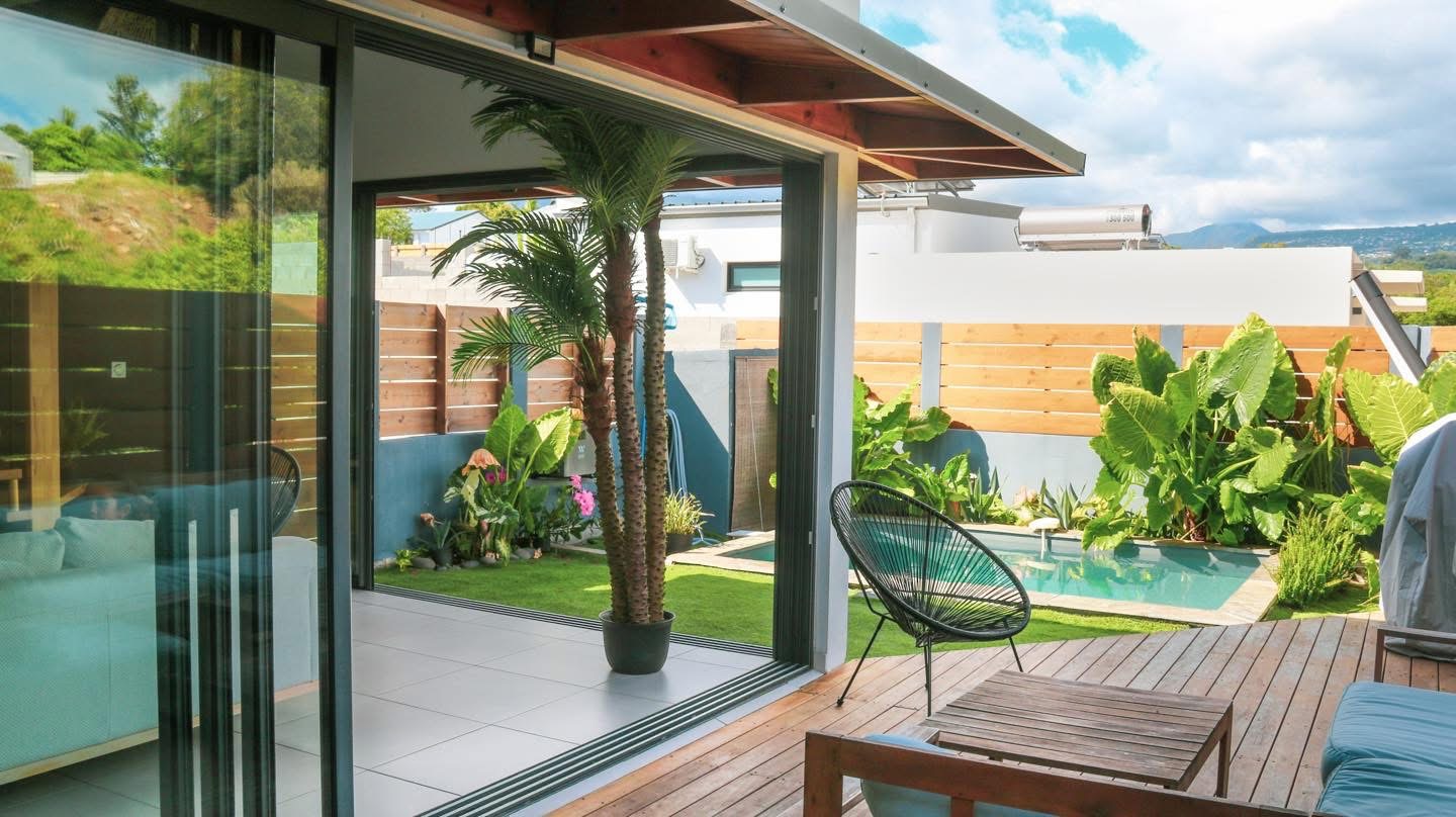Baie vitrée ouverte sur la terrasse en bois et la piscine